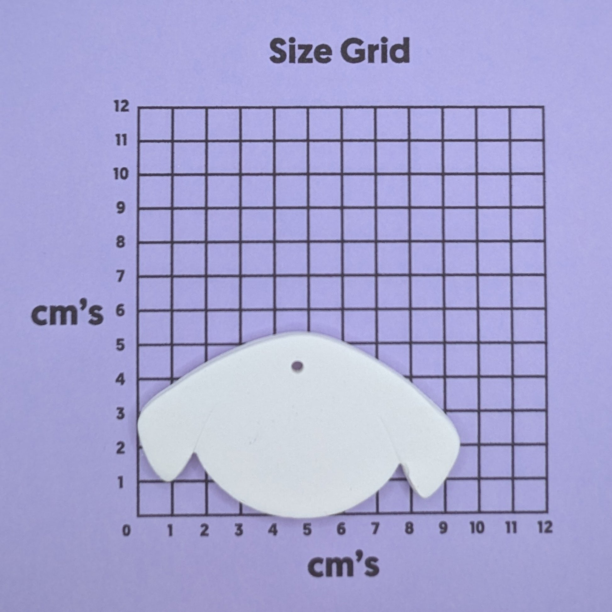 clay dog face decoration on a size grid with measurements in centimeters 