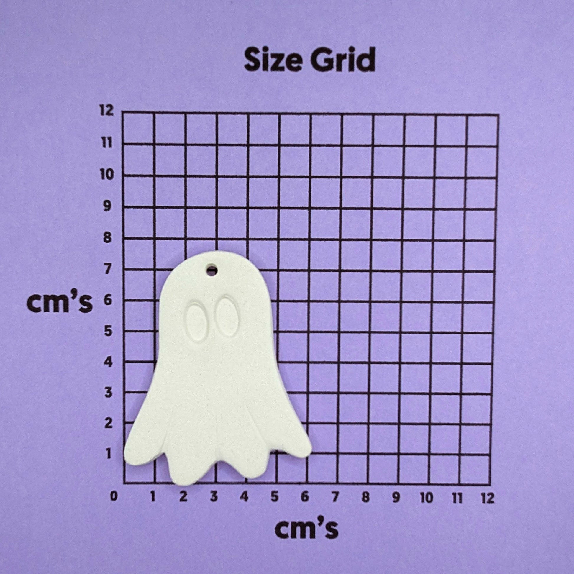 White ghost-shaped decoration on a size grid with measurements in centimeters on a purple background
