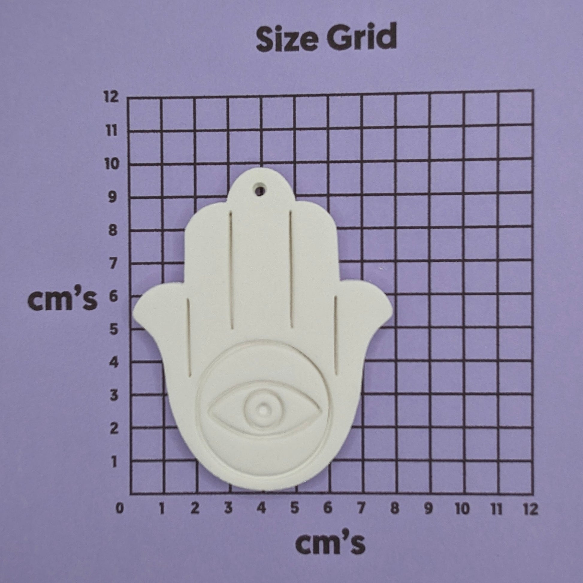 White Hamsa hand decoration on a size grid with centimeter measurements on a purple background