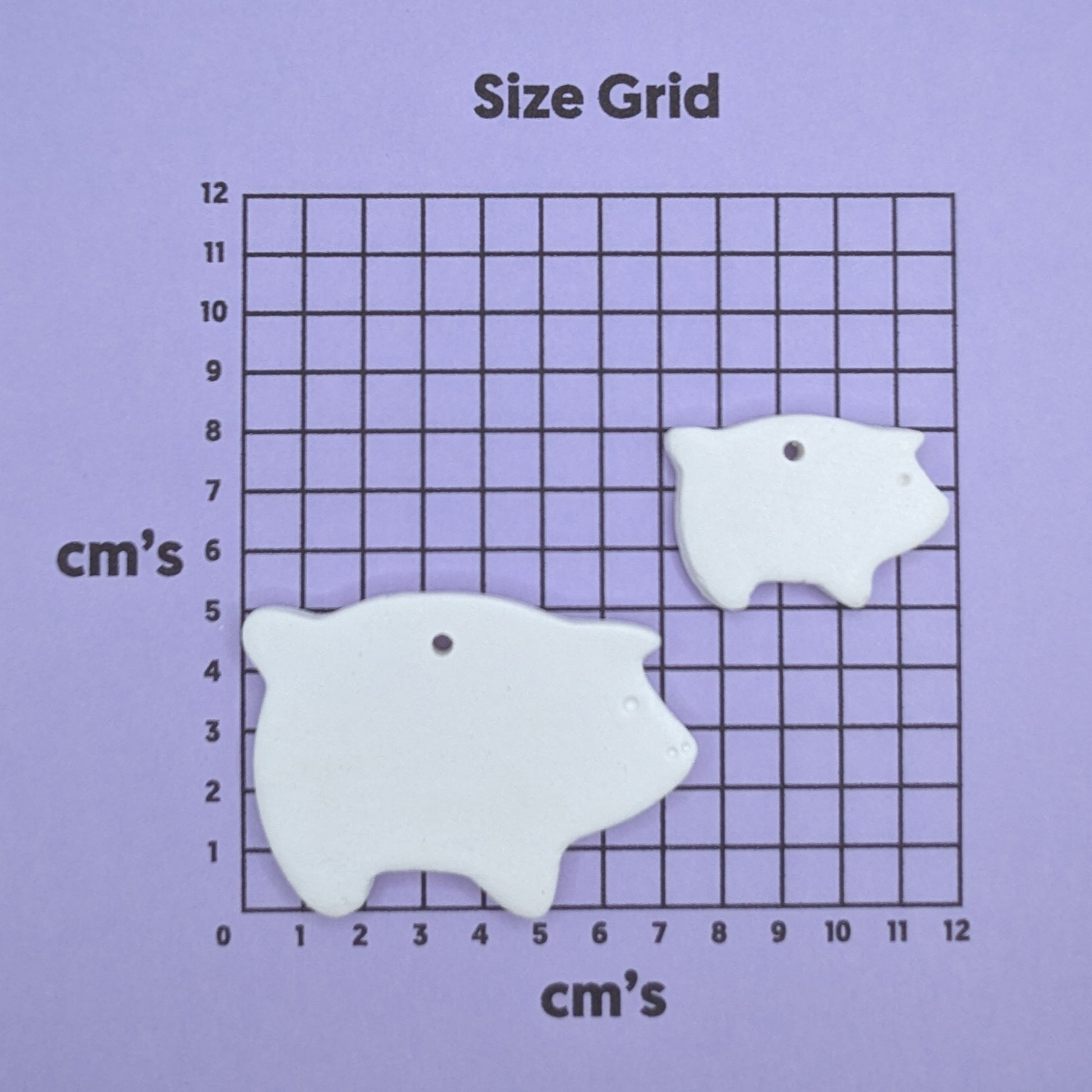 clay pig and piglet decoration on a size grid with measurements in centimeters 