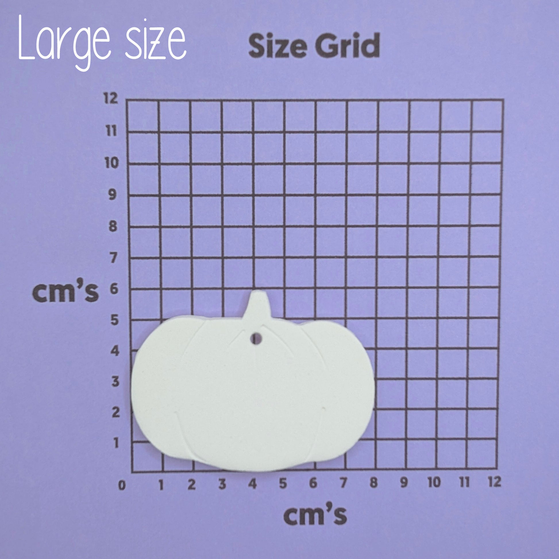 White pumpkin-shaped clay decoration on a size grid with measurements in cm