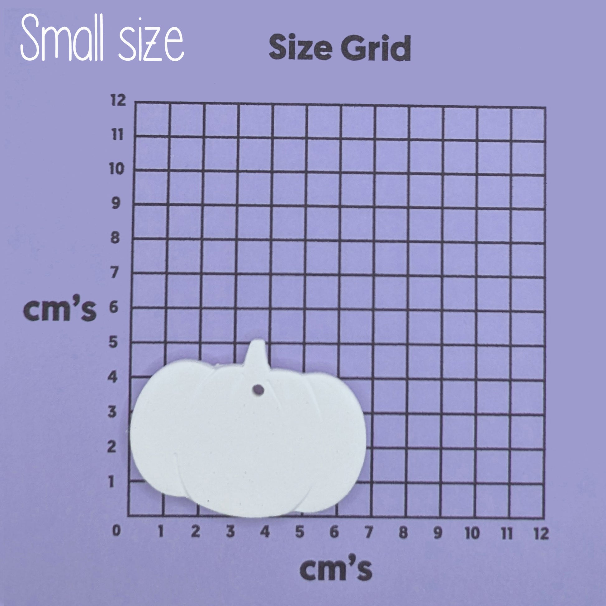 Small pumpkin-shaped clay decoration on a size grid with measurements in centimeters 