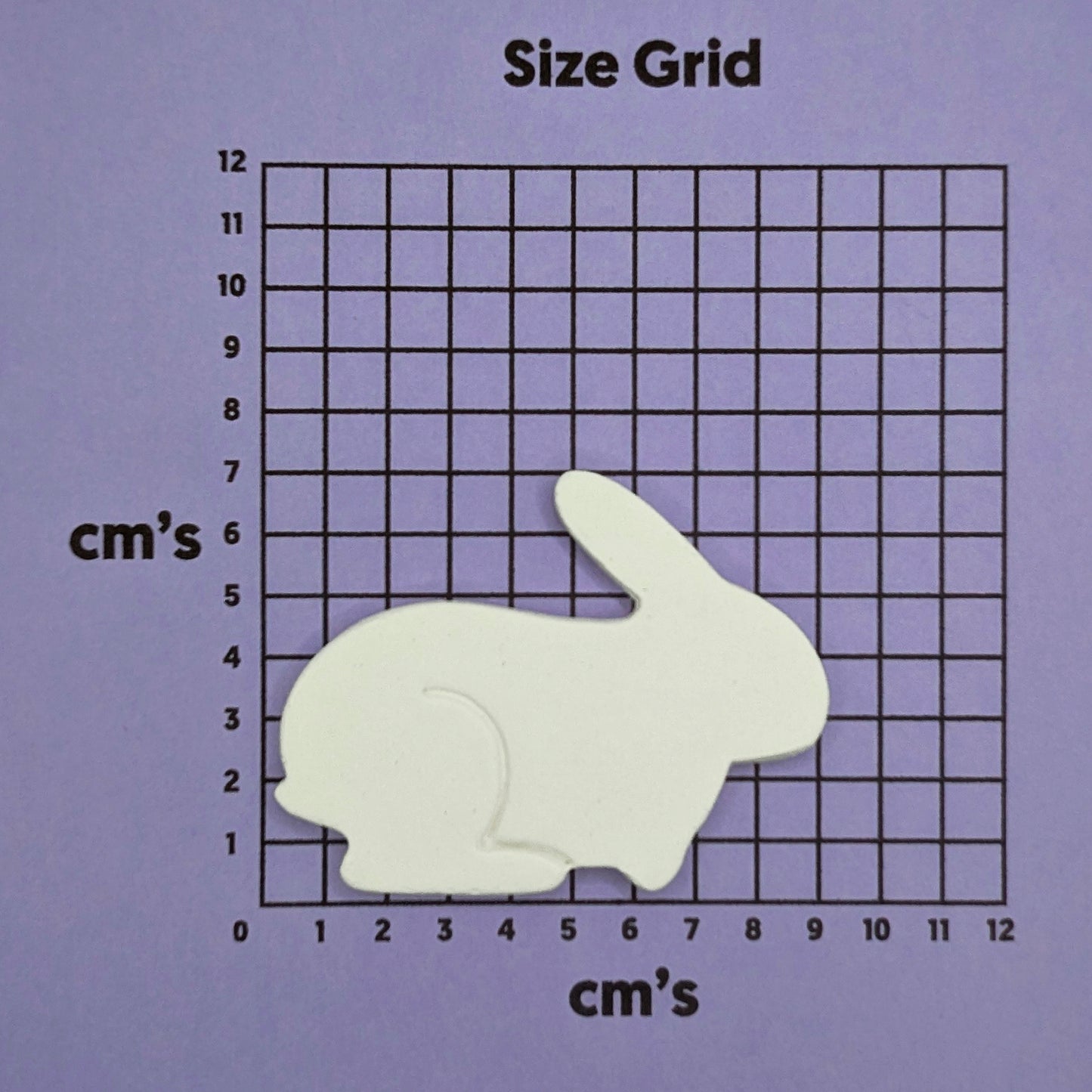 White rabbit shaped decoration on a size grid with measurements in centimeters on a purple background