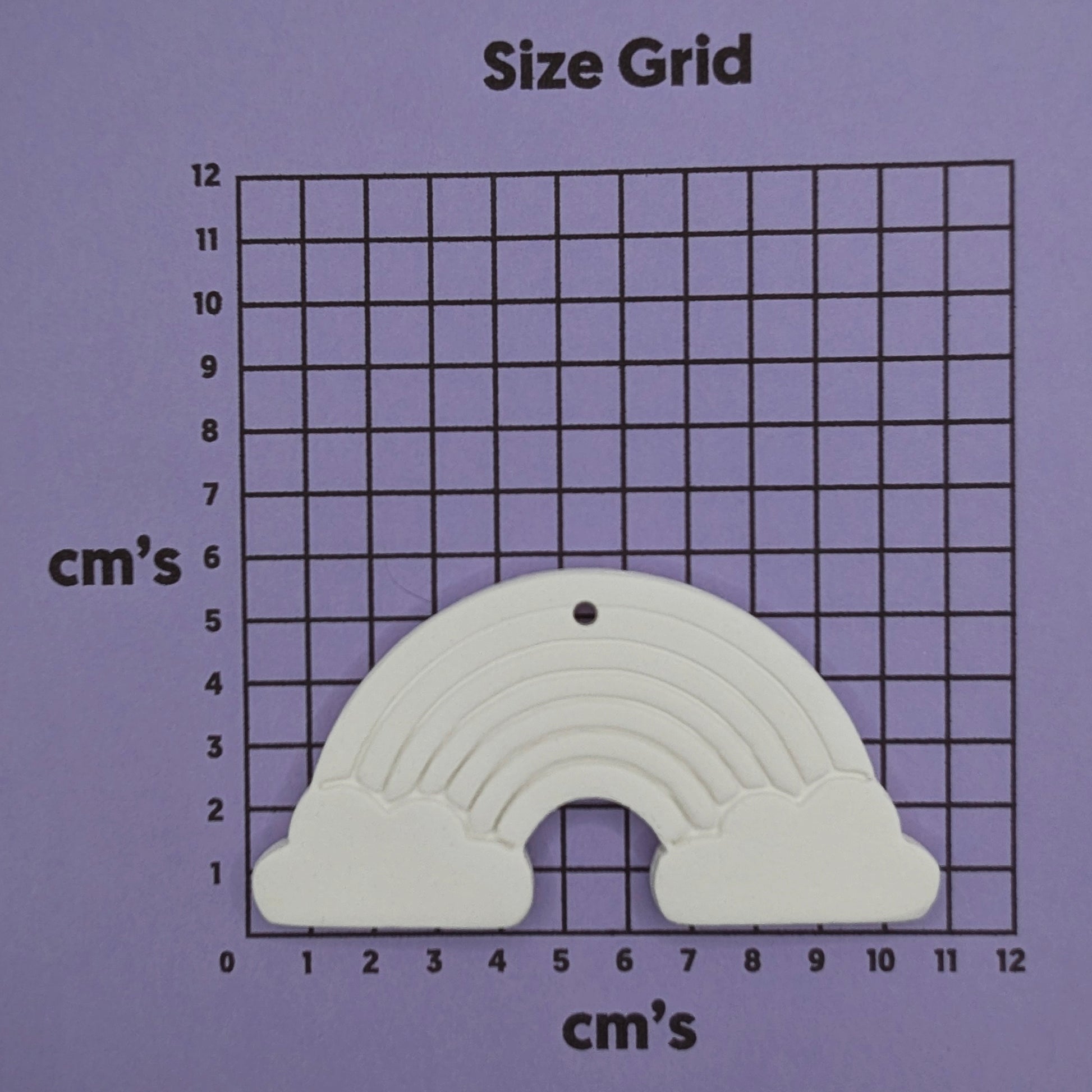 white air dried clay rainbow decoration shown on a cm size grid