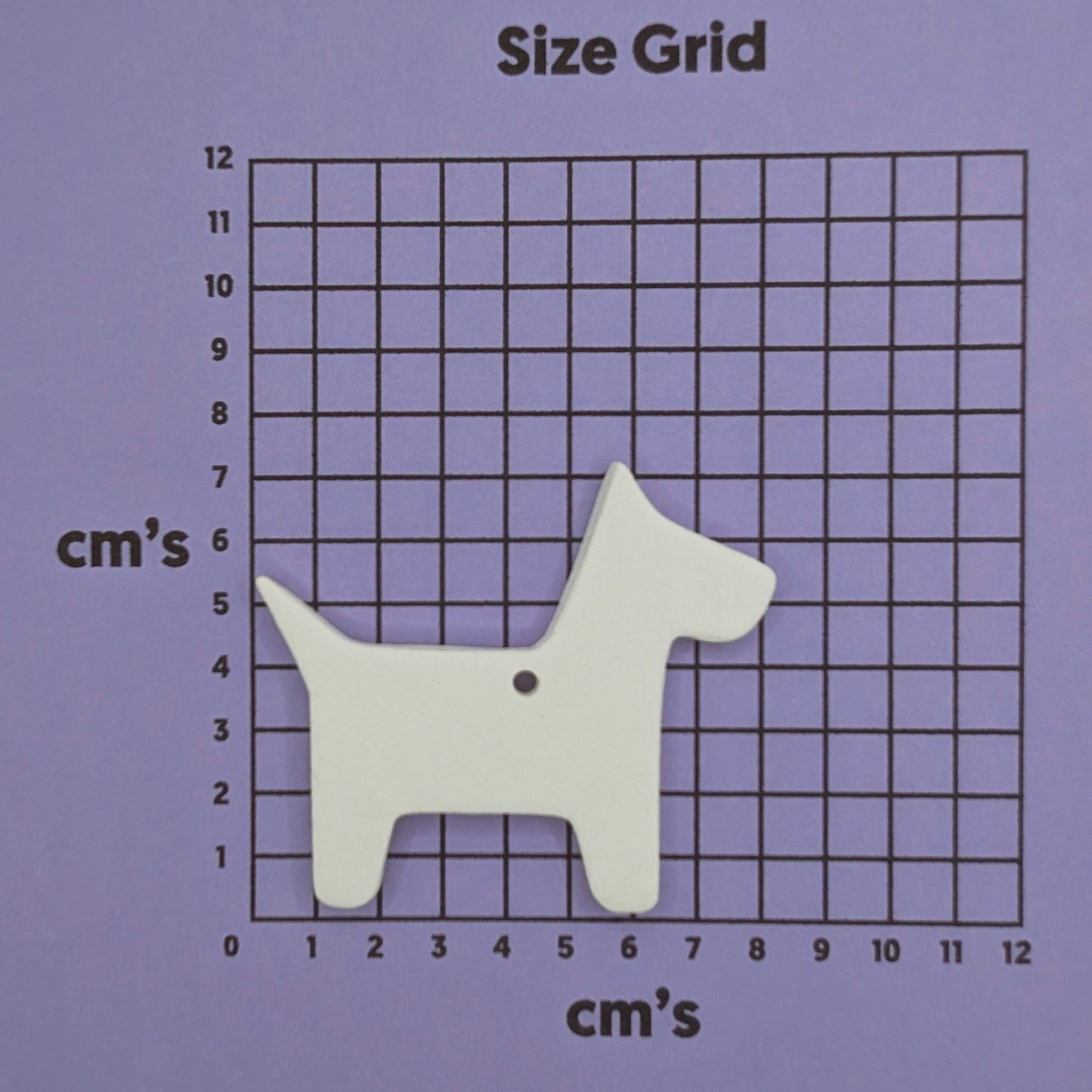 white air dried clay decoration in the shape of a scotty dog, shown on a purple cm size grid
