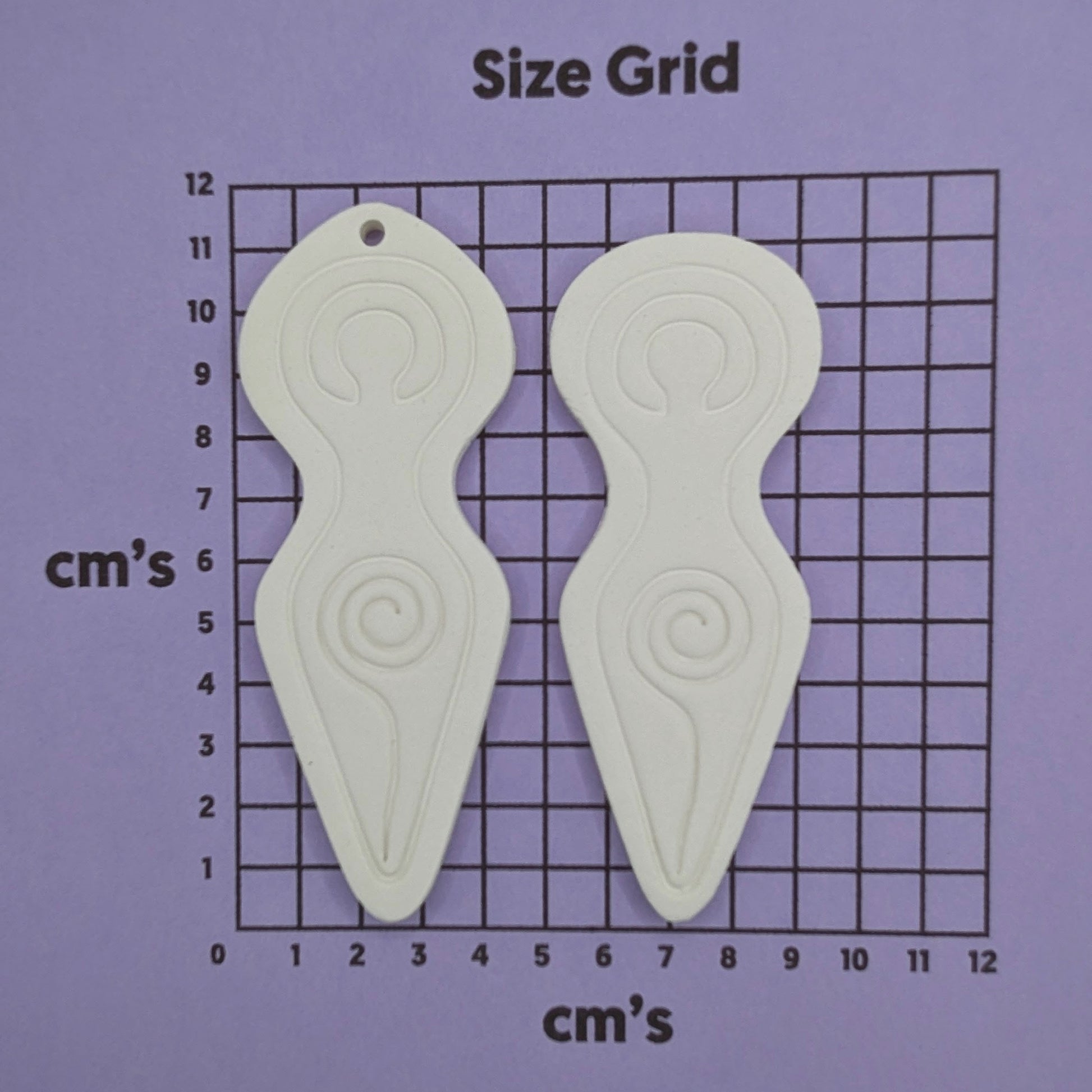 2 Spiral goddess shaped clay decoration shown on a cm size grid to show size