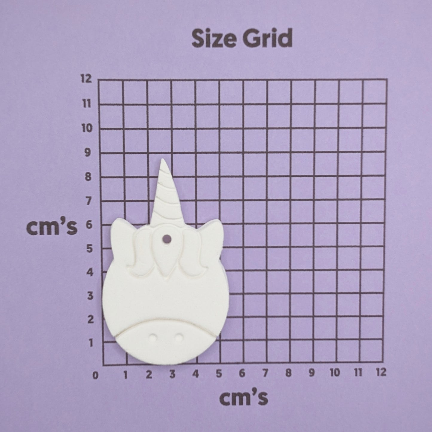 Unicorn-shaped decoration on a size grid with measurements in centimeters on a purple background