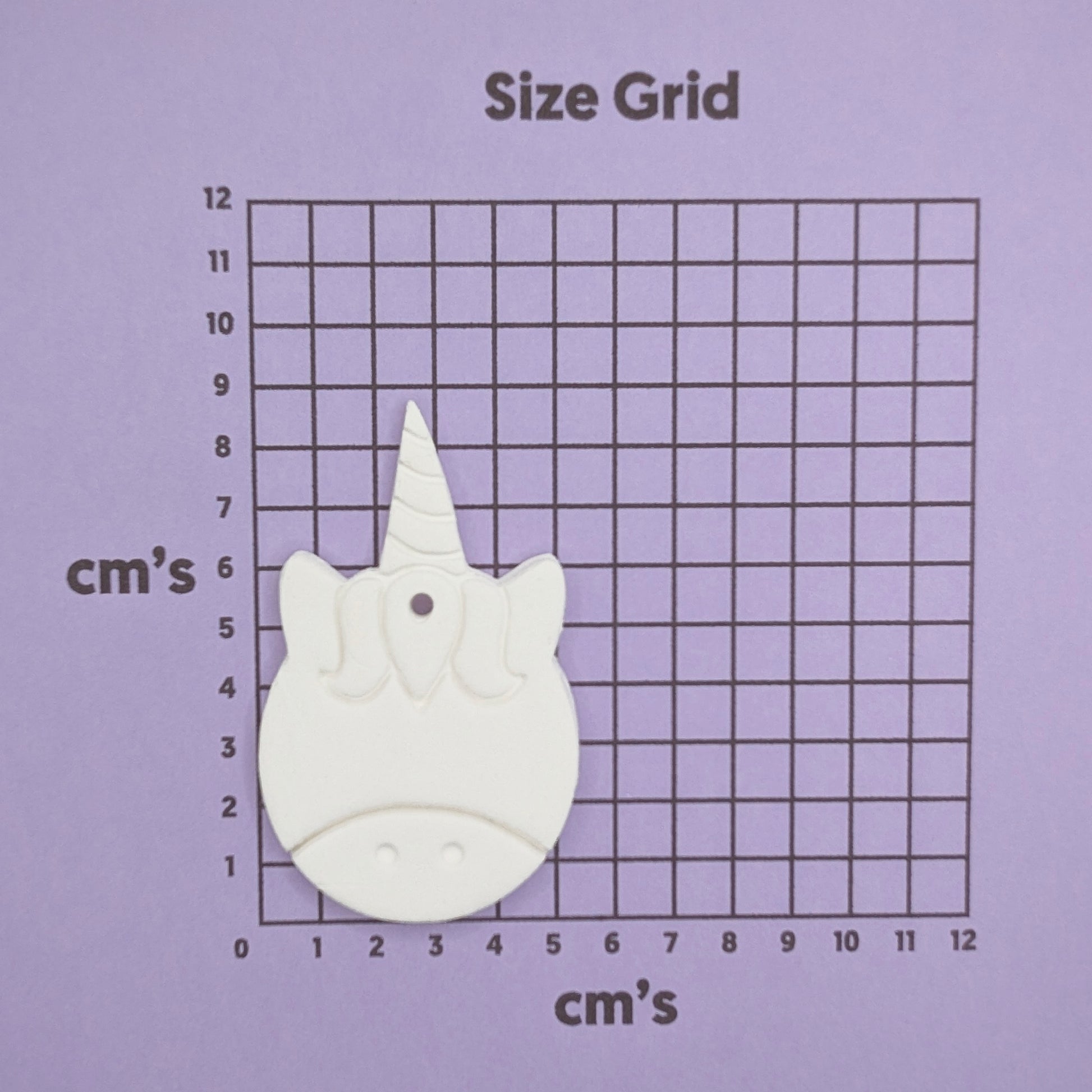 Unicorn-shaped decoration on a size grid with measurements in centimeters on a purple background