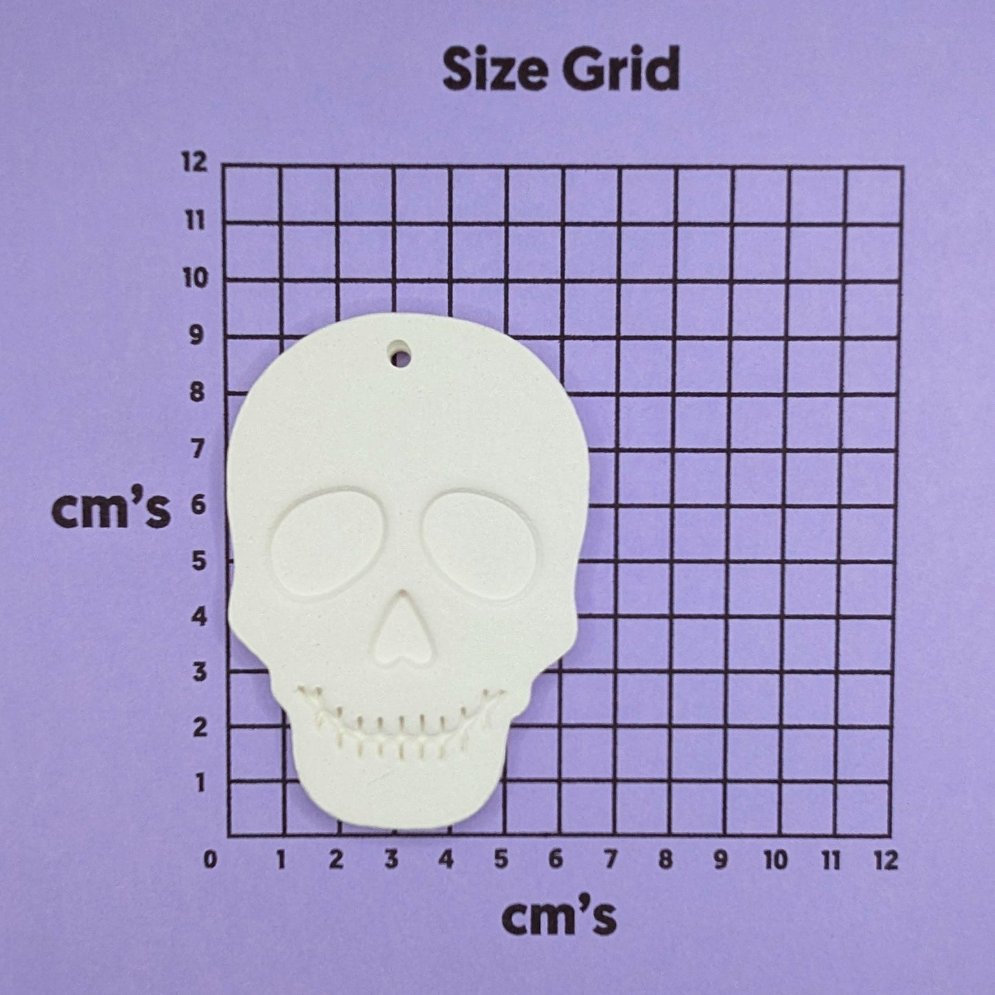 Skull-shaped decoration on a size grid with measurements in cm's
