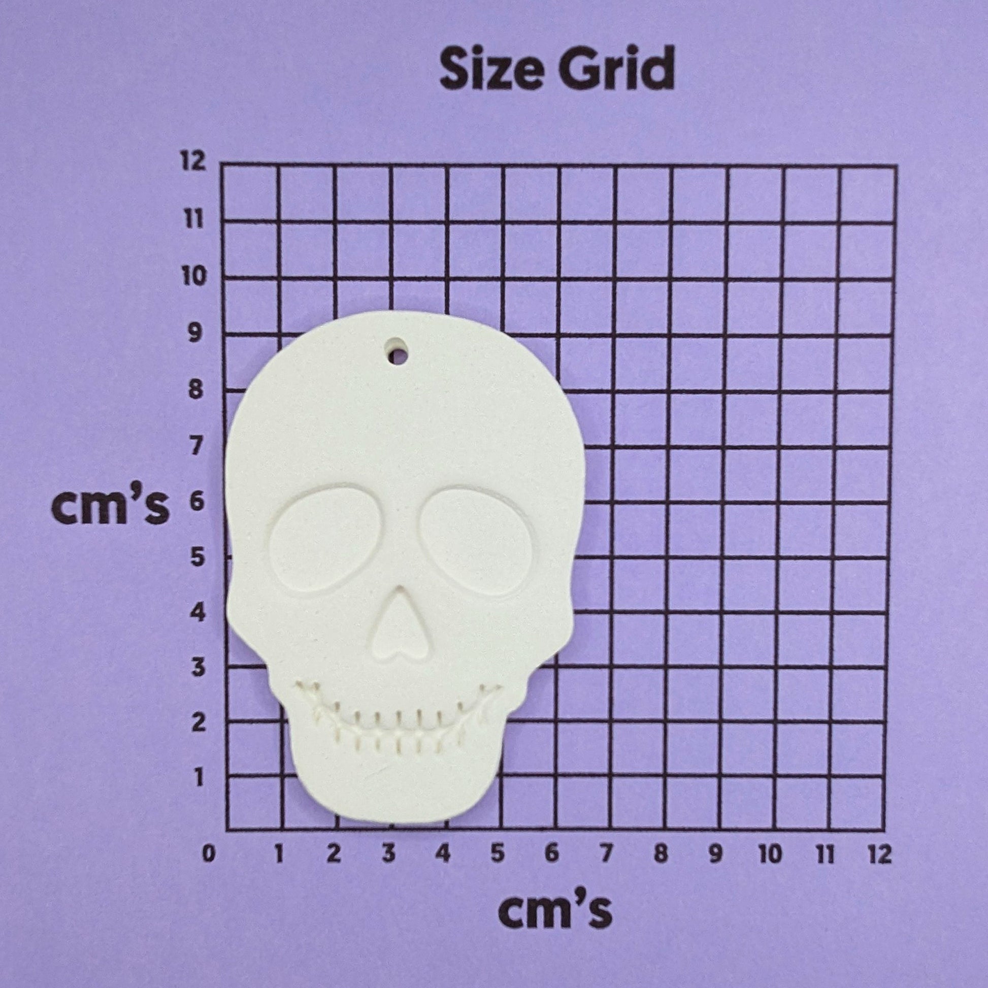 Skull-shaped decoration on a size grid with measurements in cm's