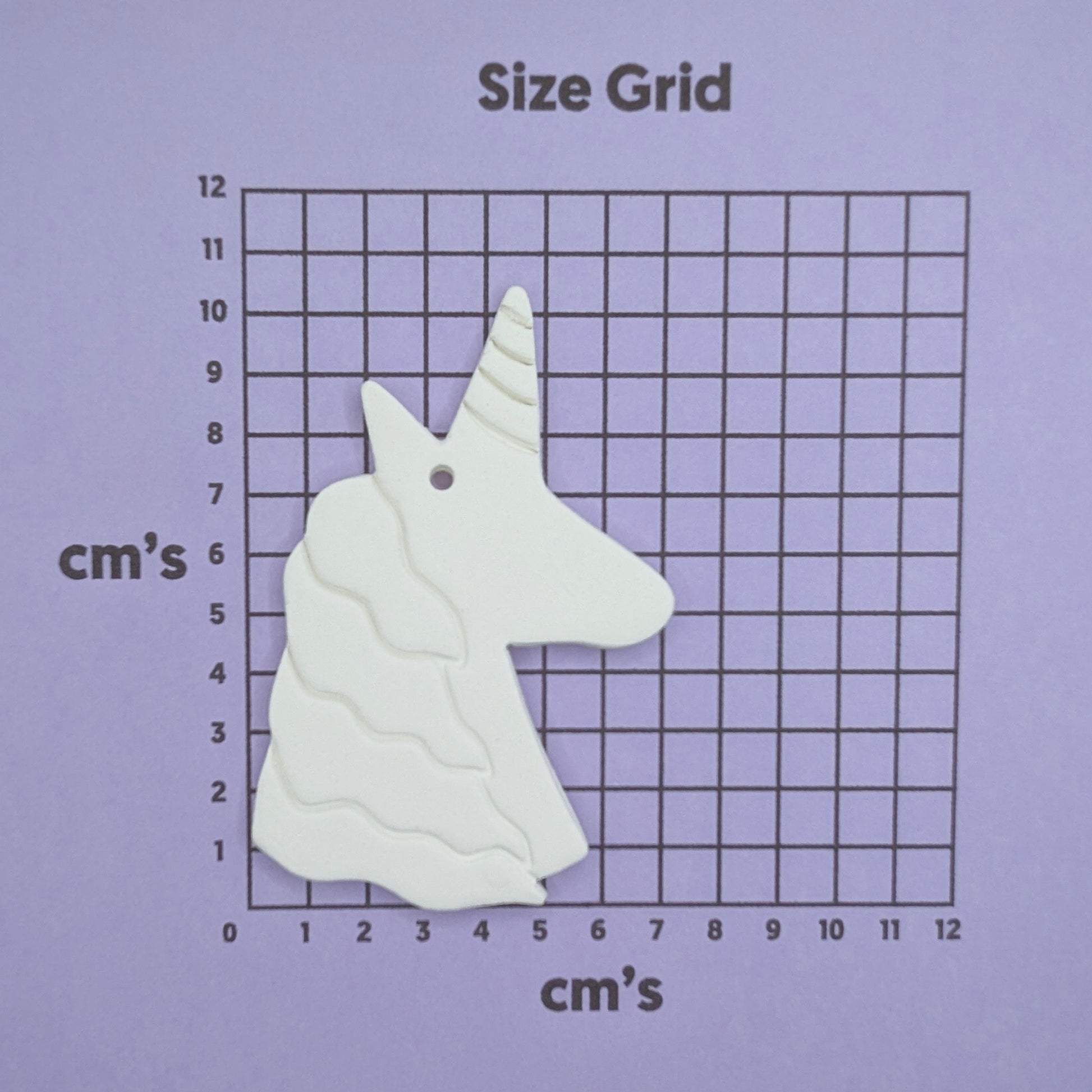 White unicorn head on a size grid with measurements in centimeters on a purple background