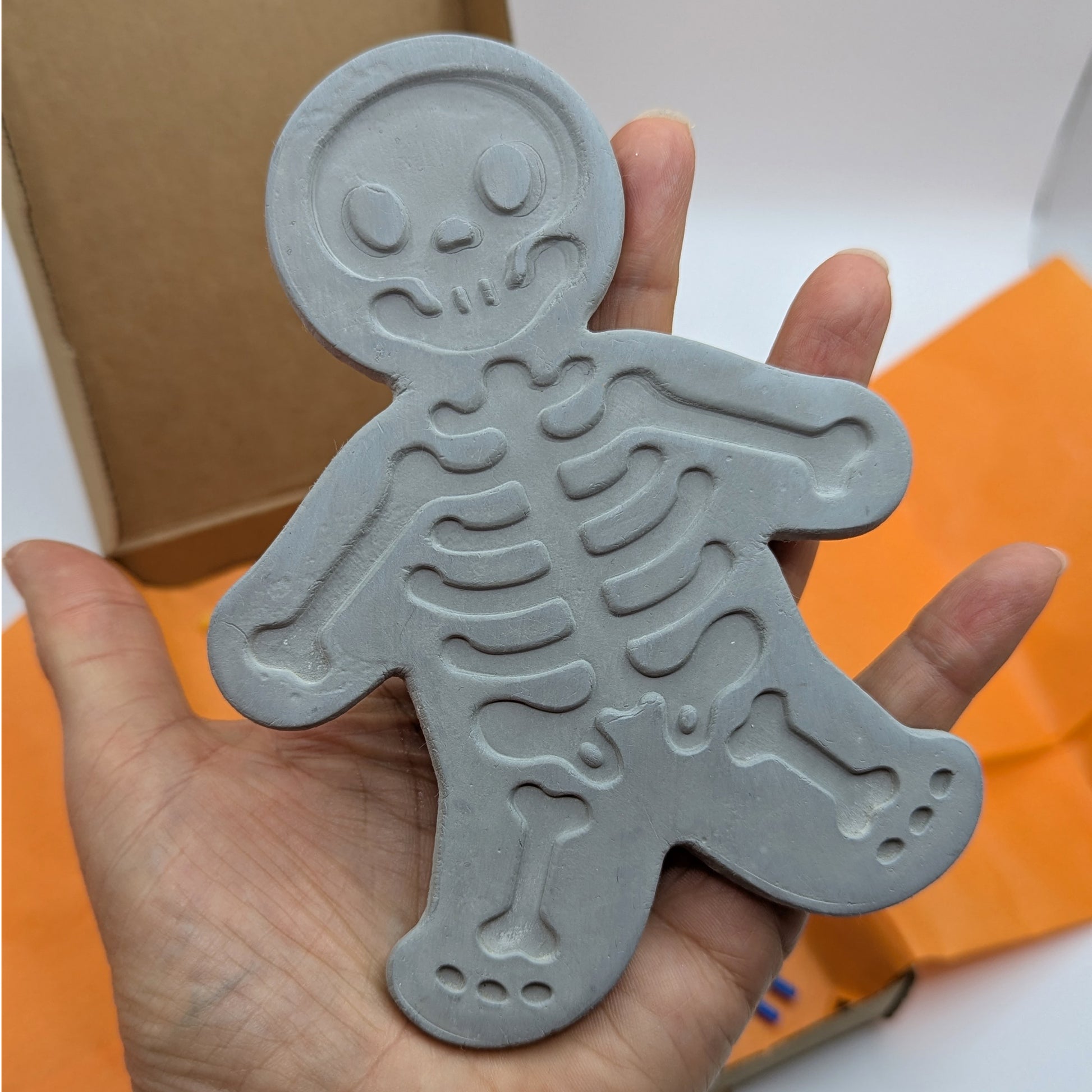 close up of grey clay decoration in the shape of a skeleton