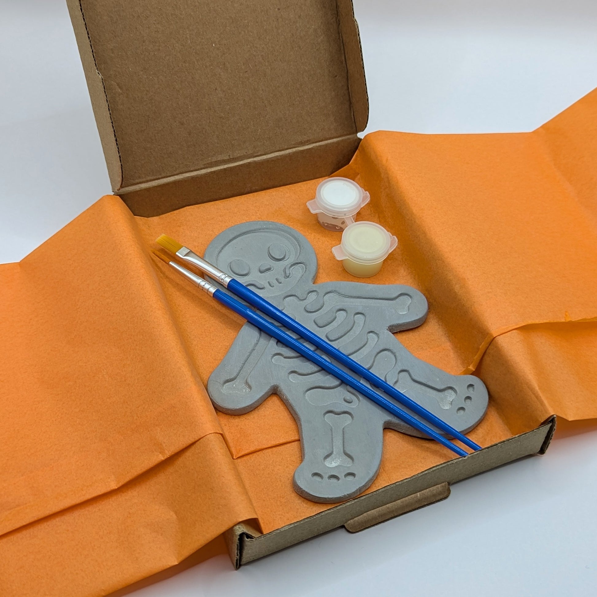 glow in the dark skeleton kit, containing clay decoration, 2 paints, 2 brushes, comes in a box wrapped in tissue paper