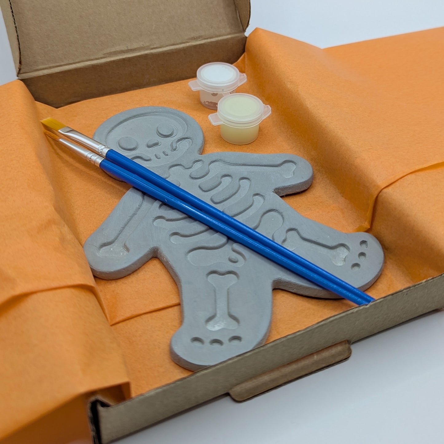 close up of skeleton clay kit, with glow in the dark paint and brushes