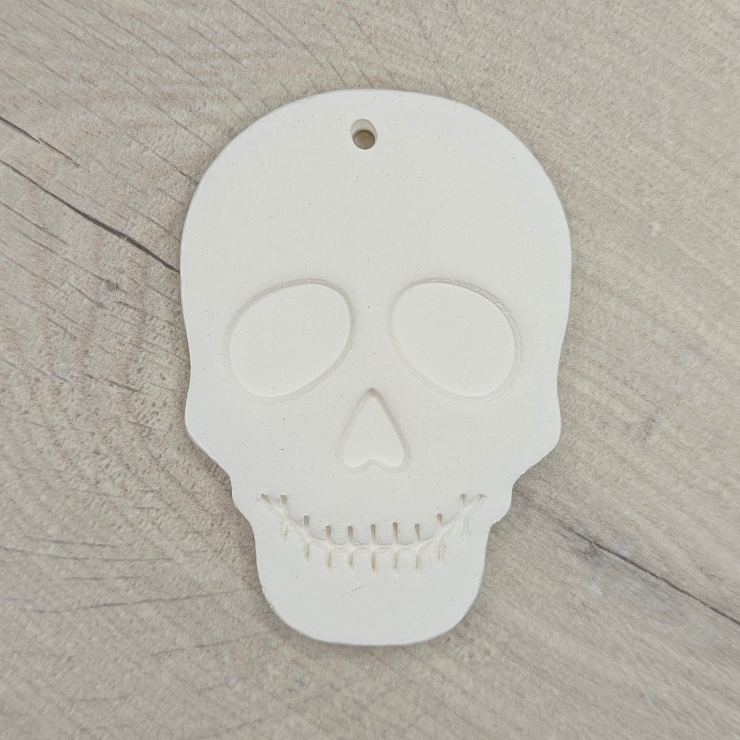 White skull-shaped clay decoration on a wooden surface