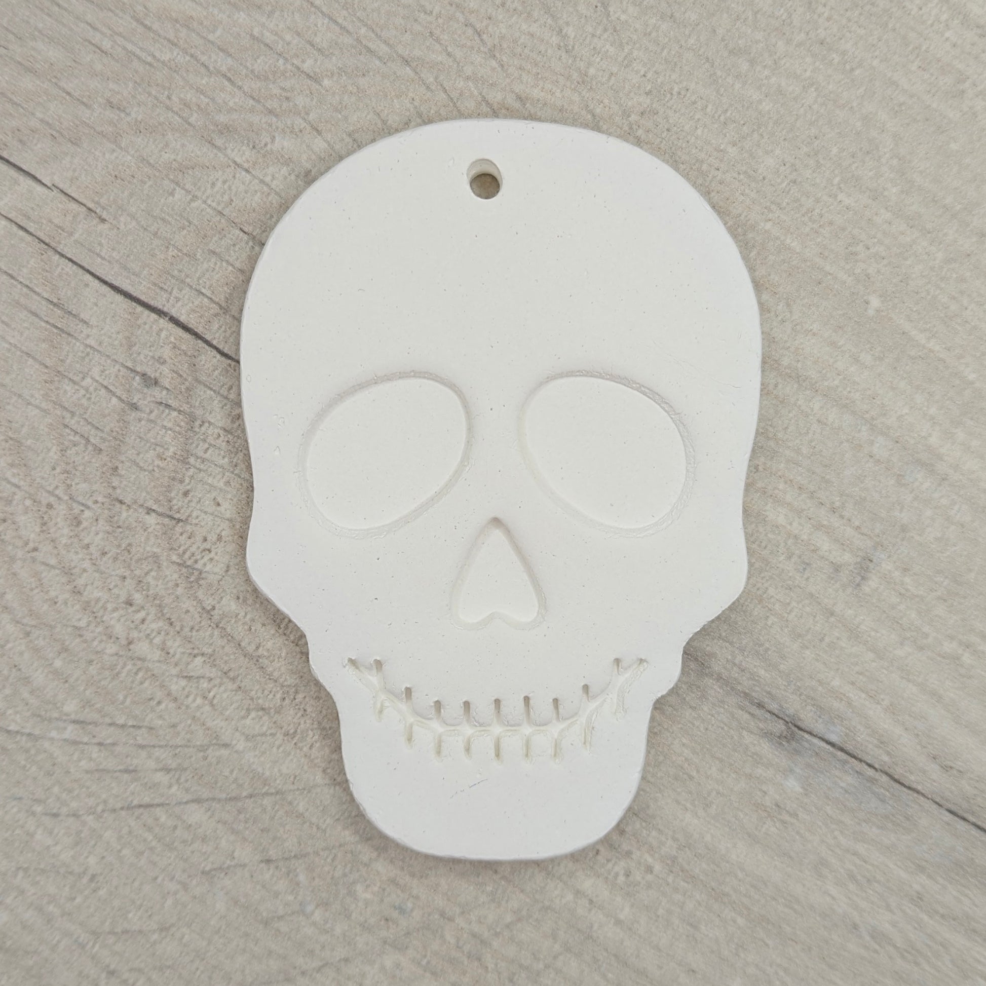 White skull-shaped clay decoration on a wooden surface