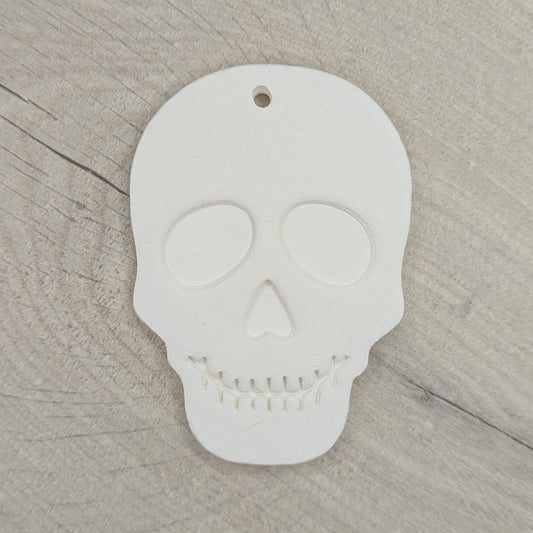 White skull-shaped clay decoration on a wooden surface