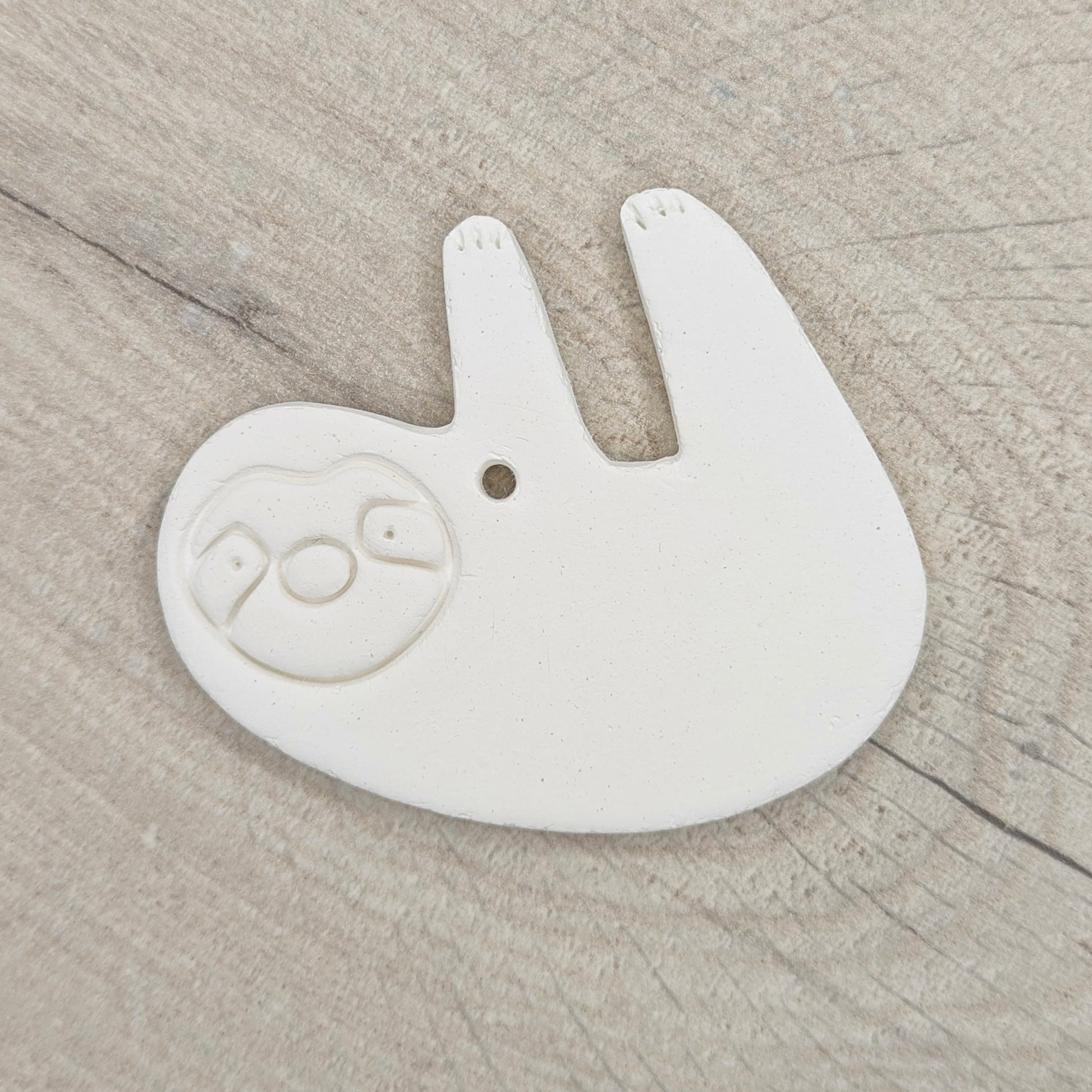 Sloth clay decoration on a ligh wood background