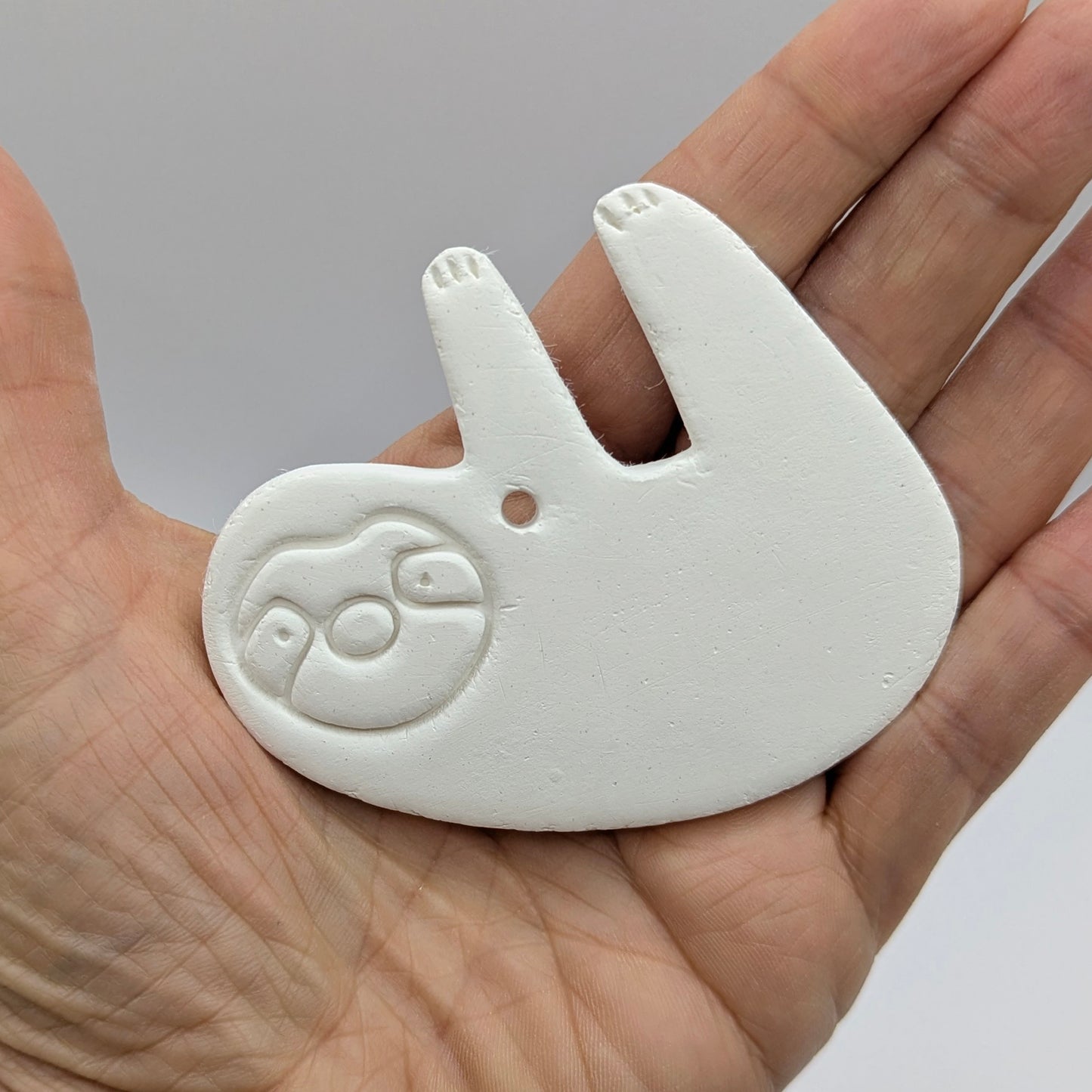 clay sloth decoration been held in a hand to show size