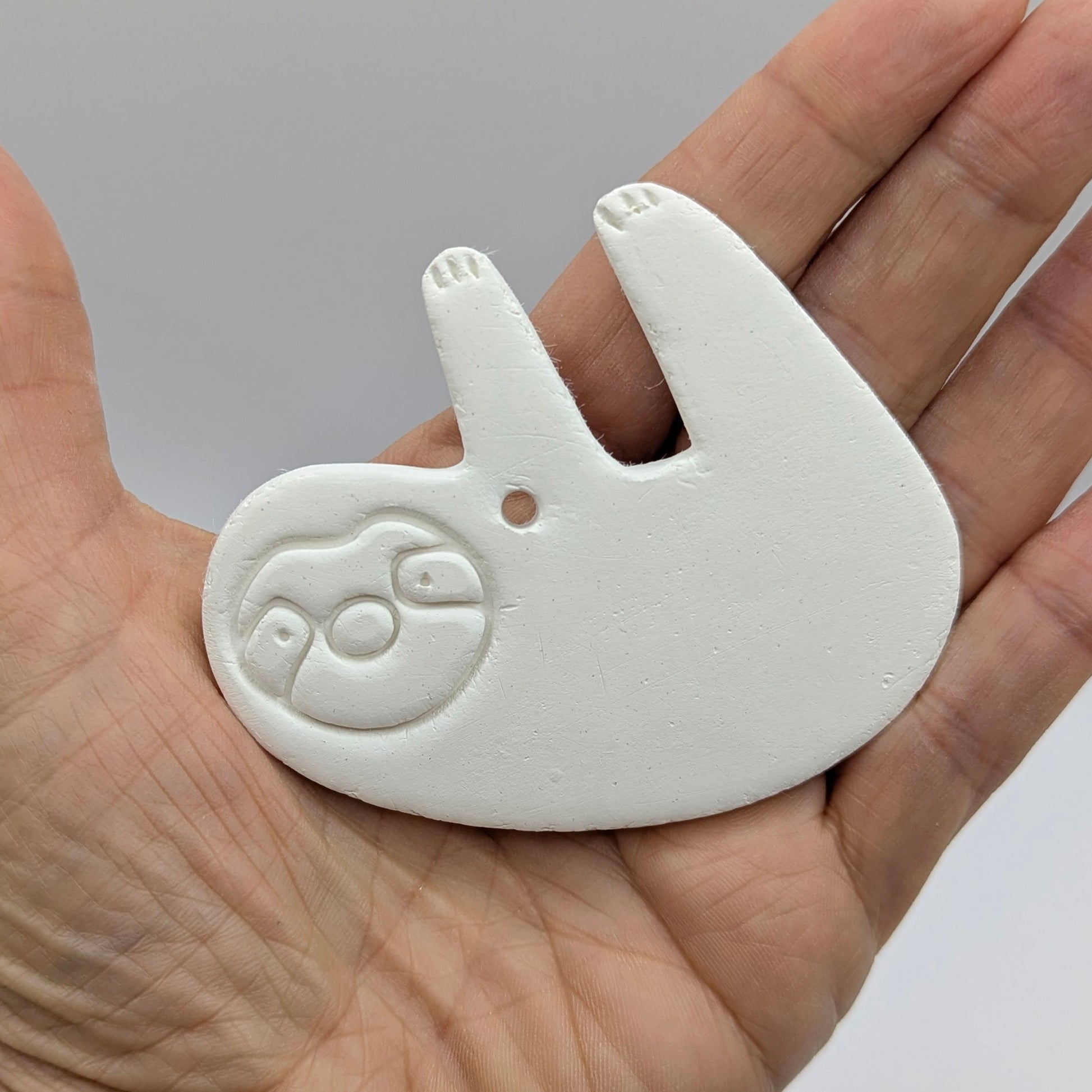 clay sloth decoration been held in a hand to show size