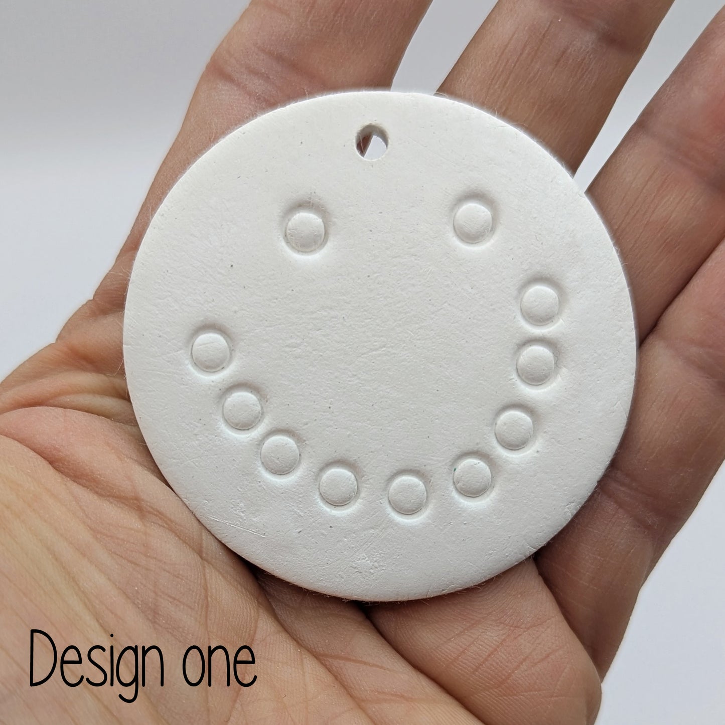 snowman face - design 1, made of air dried clay, shown in palm of hand