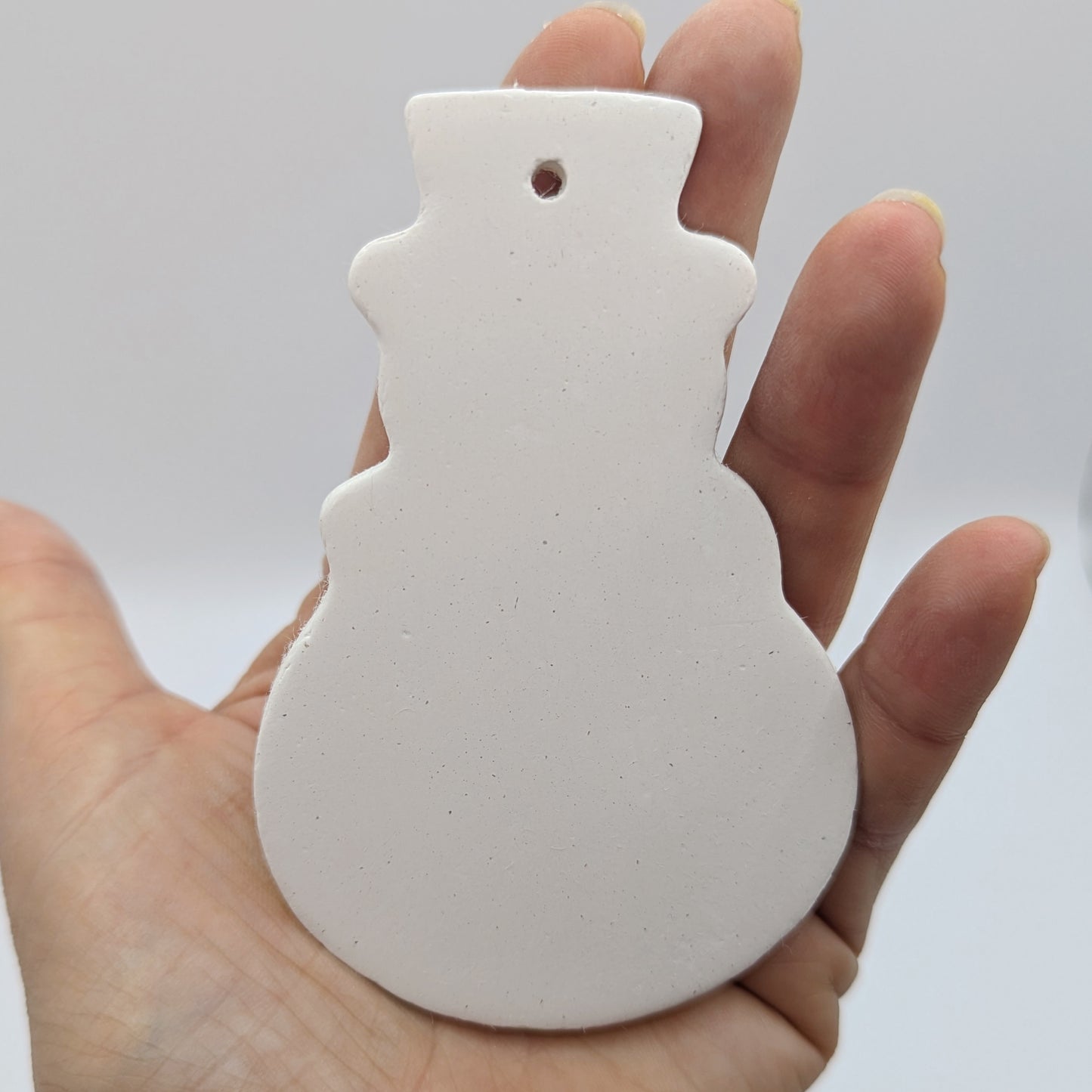 plain snowman clay decoration held in palm of hand