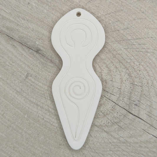 Spiral goddess shaped clay decoration with a hanging hole above her head area, shown on a light wood background