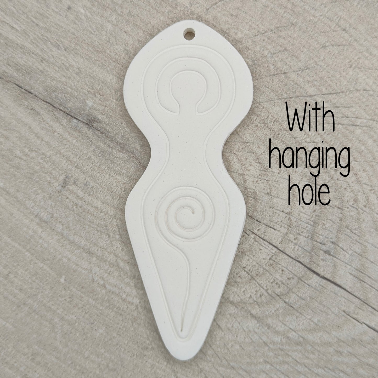 Spiral goddess shaped clay decoration shown on a light wood  background with wording 'with hanging hole'