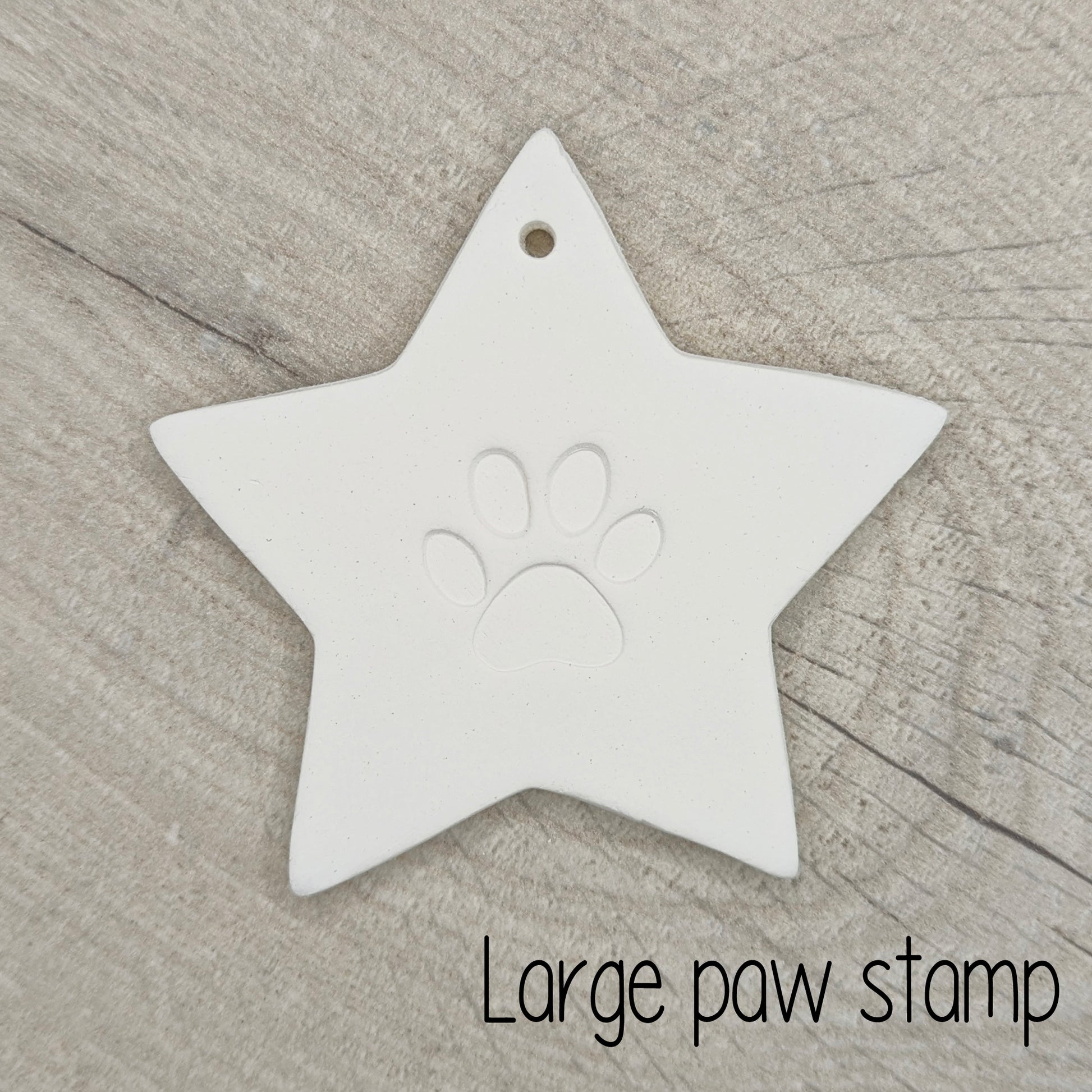 Star shaped clay decoration with a large paw print design in the centre on a wooden surface