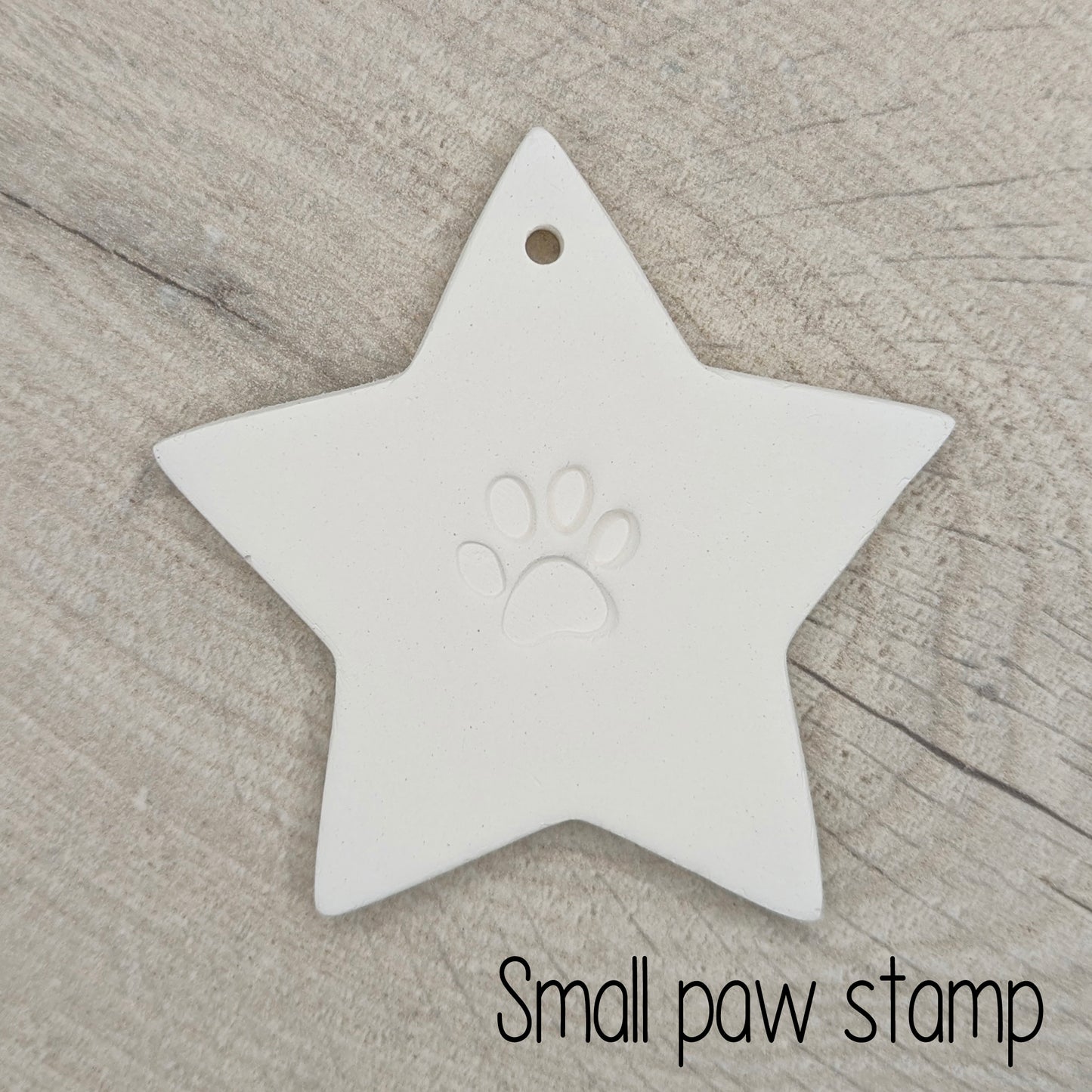 Star shaped clay decoration with a small paw print design in the centre on a wooden surface