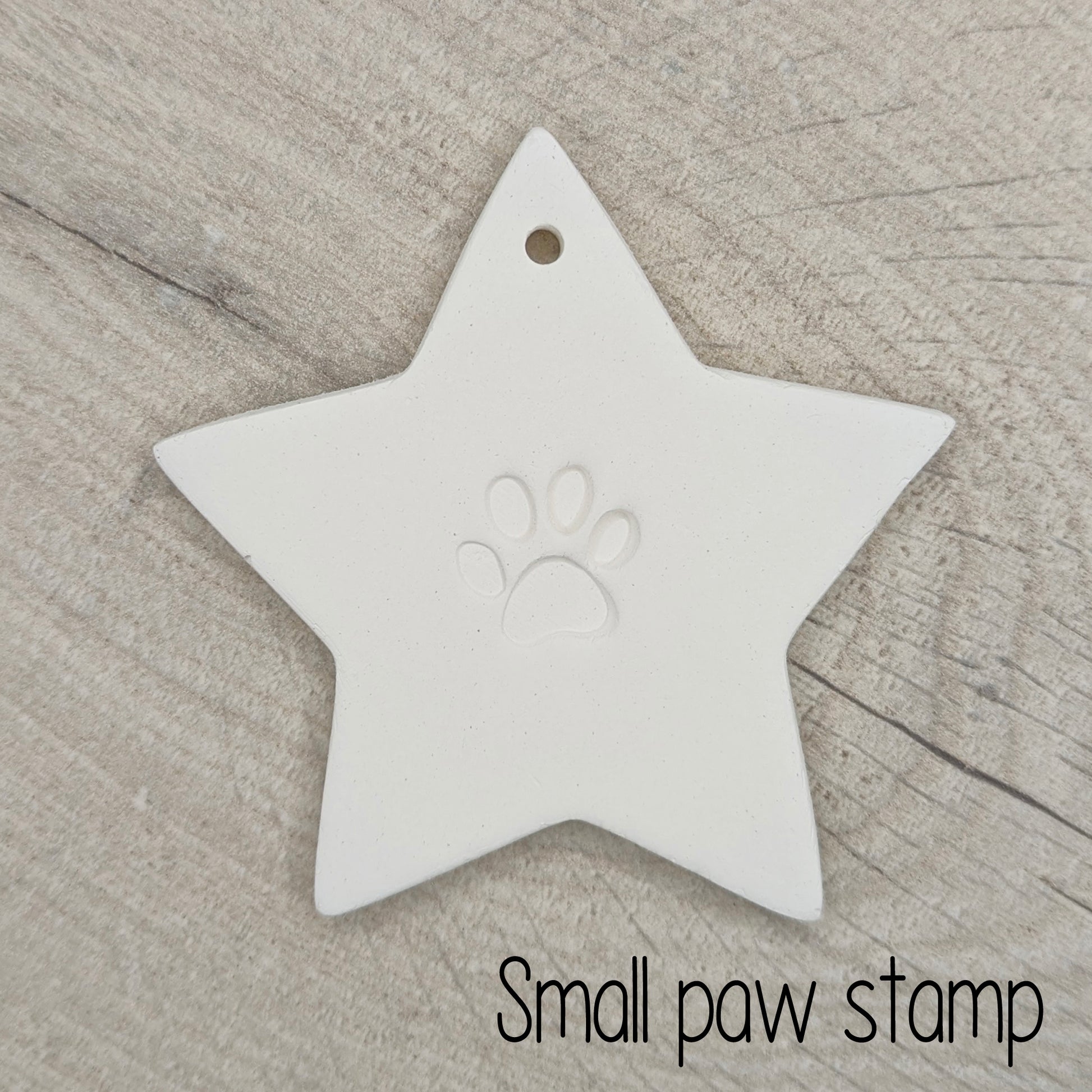 Star shaped clay decoration with a small paw print design in the centre on a wooden surface