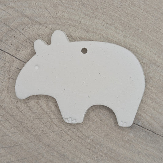 clayed decoration in the shape of a tapir, with little claws and eyes stamped into the clay, shown on a wooden background