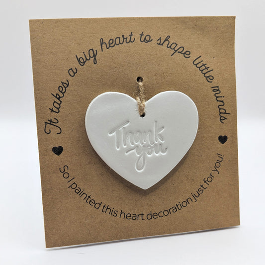 'It takes a big heart to shape little minds' text on a brown kraft card with  a clay heart decoration with 'Thank you wording' stamped into the clay, which is  attached for you to paint and decorate