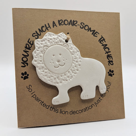 'You're such a roar-some teacher' text on a brown kraft card with  a clay lion decoration attached for you to paint and decorate