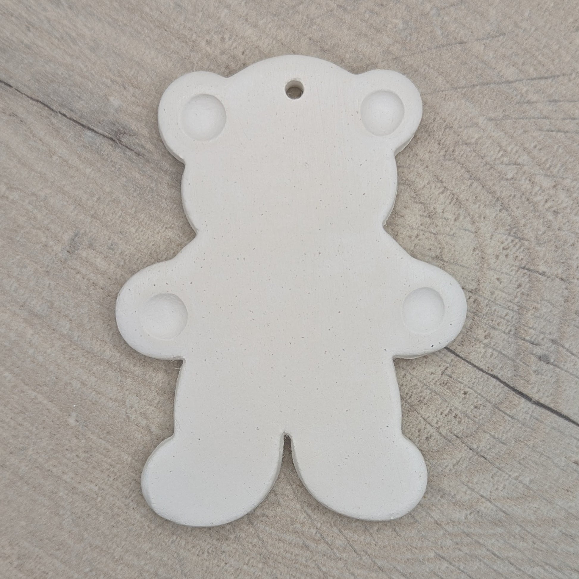 White clay decoration in the shape of a teddy bear with ears  and paws stamped on