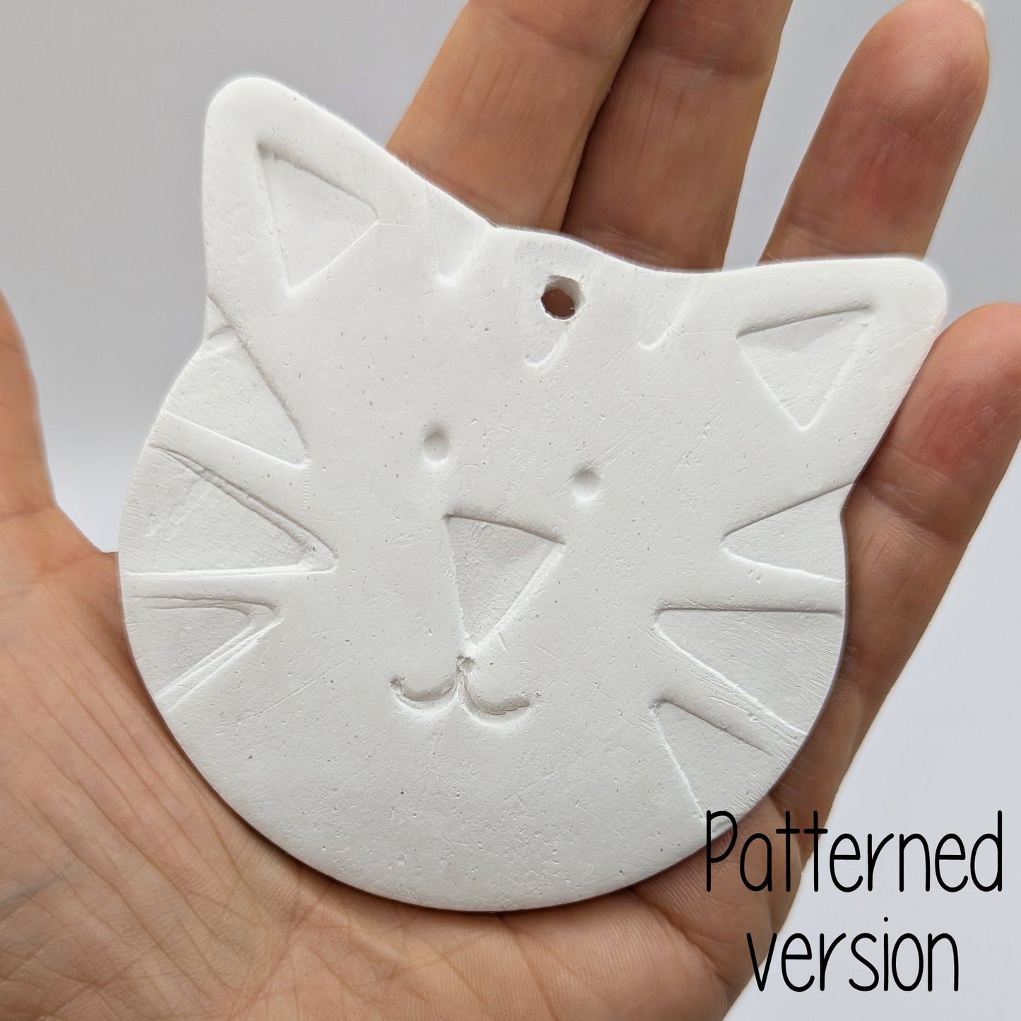 tiger or large cat face clay decoration being held in a hand to show size 