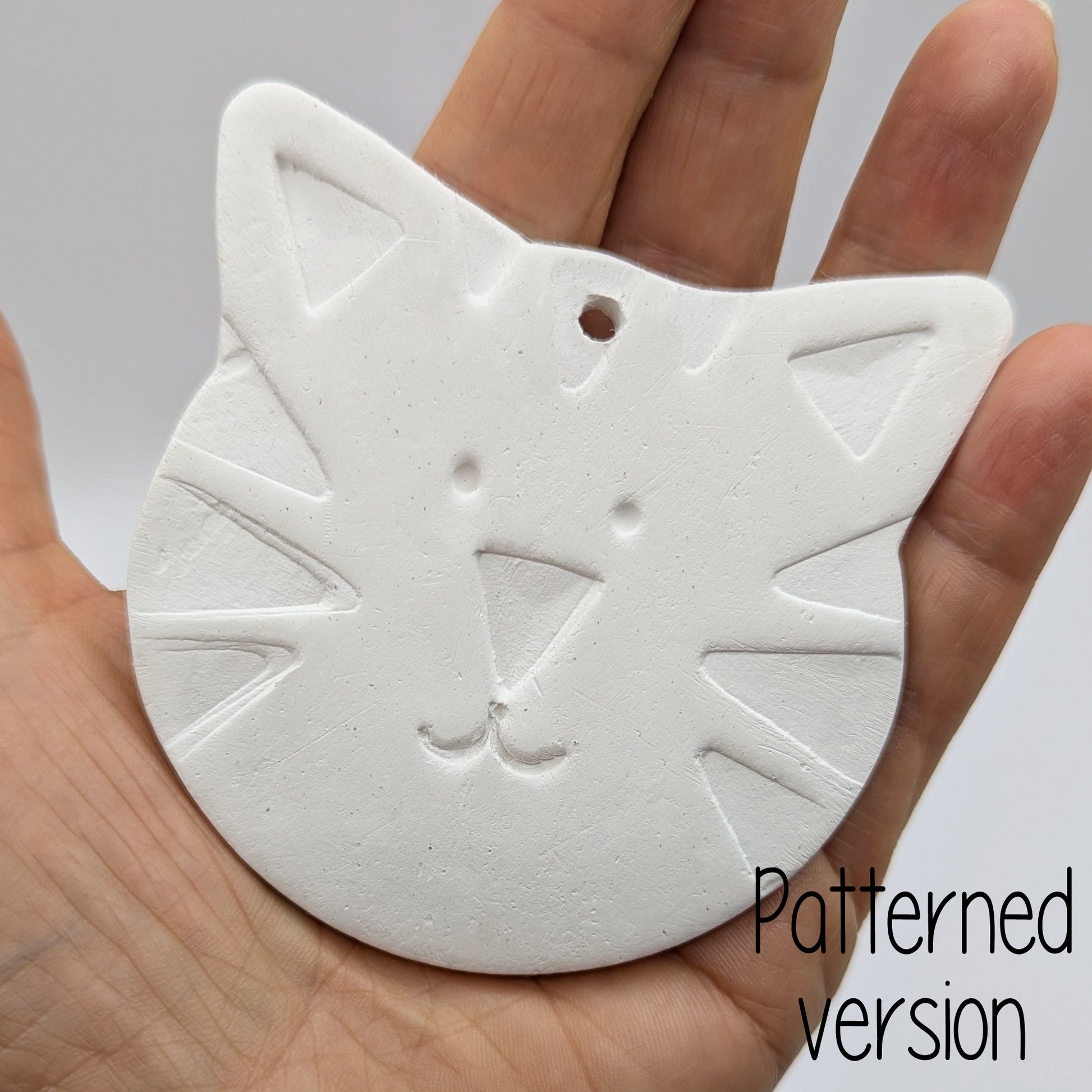 tiger or large cat face clay decoration being held in a hand to show size 
