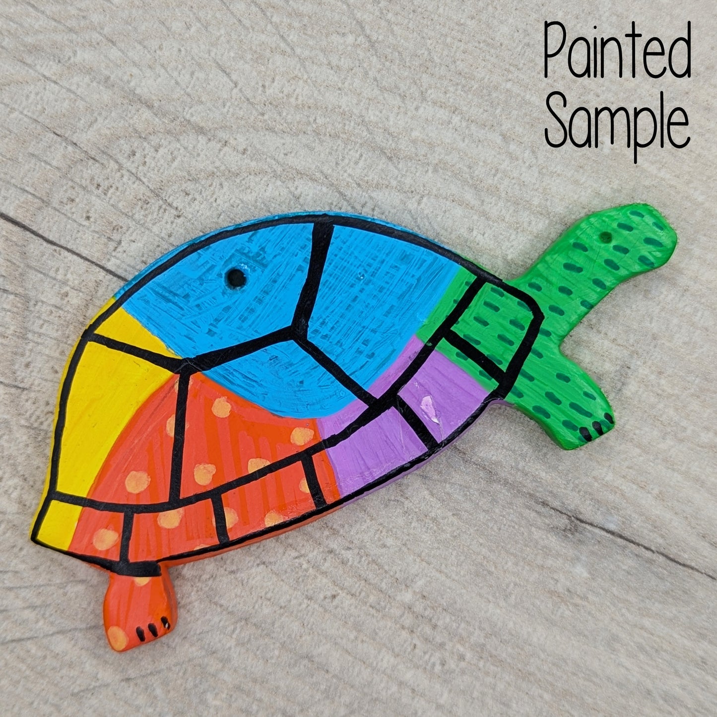 sample of painted tortoise, painted in bright colours of green, blue, purple, orange and yellow with a black shell outline
