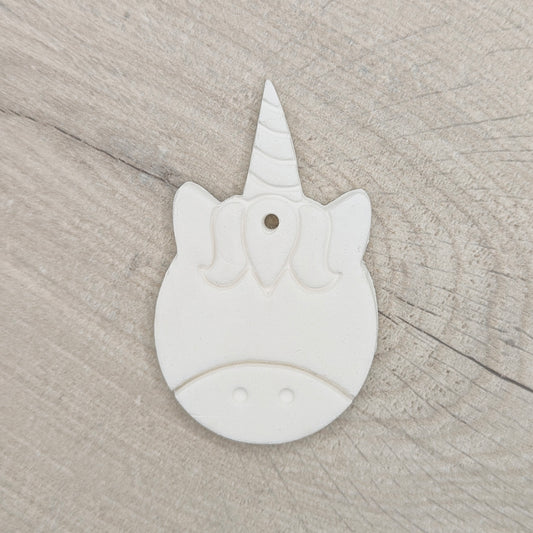 Unicorn-shaped white clay decoration on a wooden surface