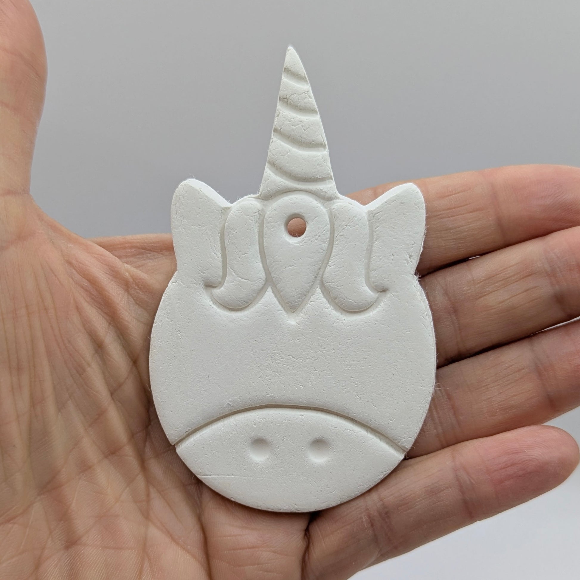 White unicorn-shaped decoration held in a hand against a plain background