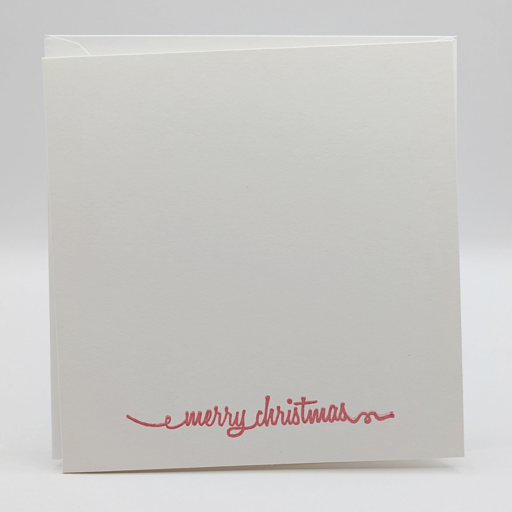 merry Christmas in a script font, stamped in red ink onto a white card comes with matching envelope