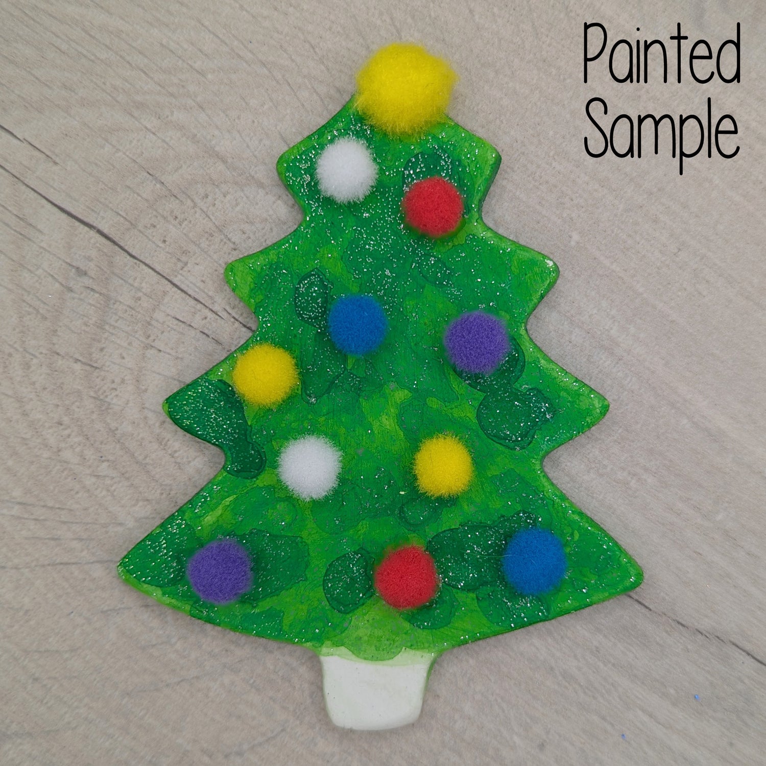 sample of painted and decoratede Christmas tree ornament / decoration decorated with colorful pom-poms and glitter green paint