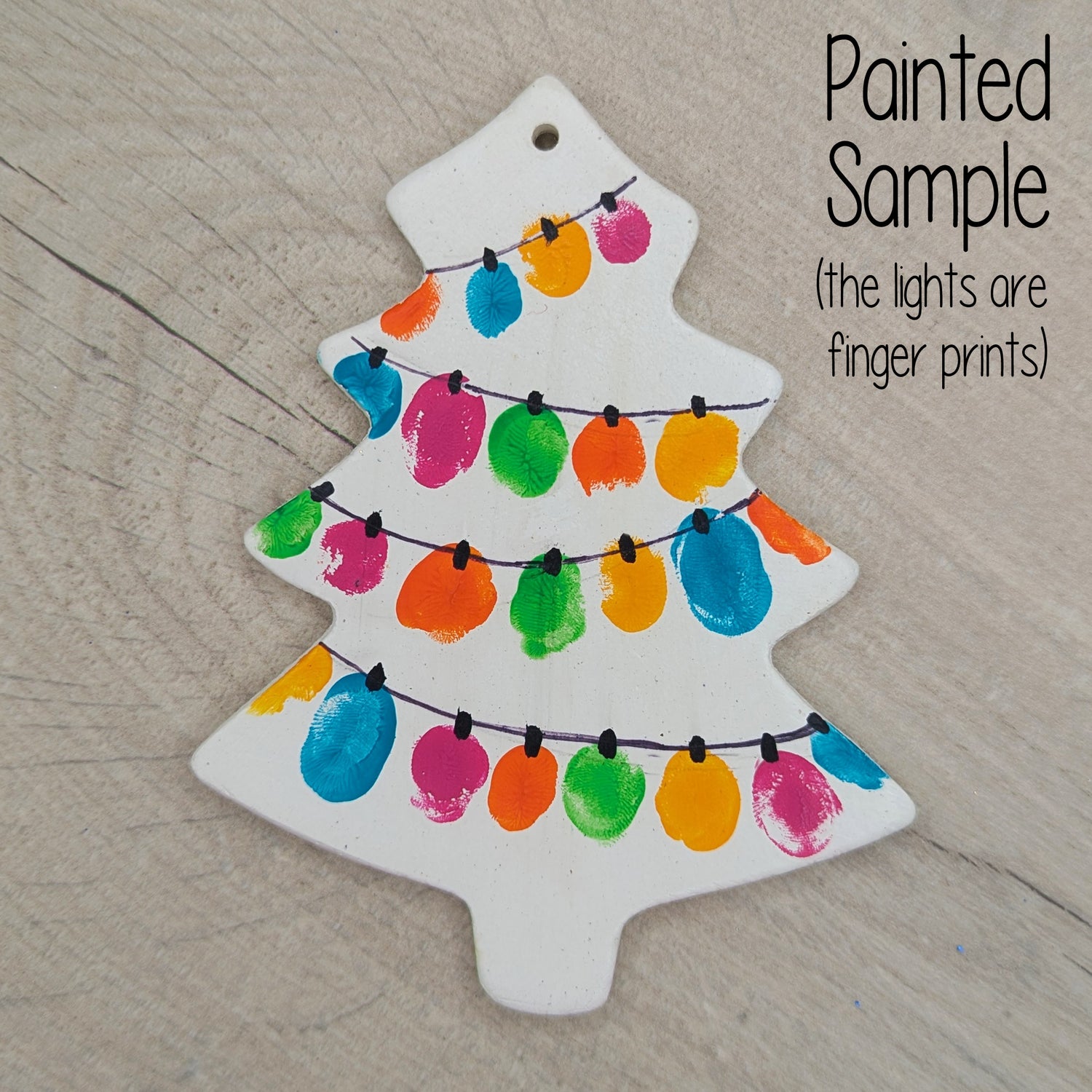 sample of painted Christmas tree decoration, made of white air dried clay and then painted using finger prints to look like fairy lights with a black pen line connecting them