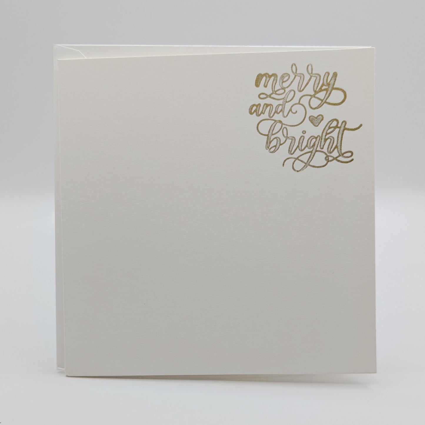 wording 'merry and bright' in a script font, stamped in gold ink onto a white card comes with matching envelope