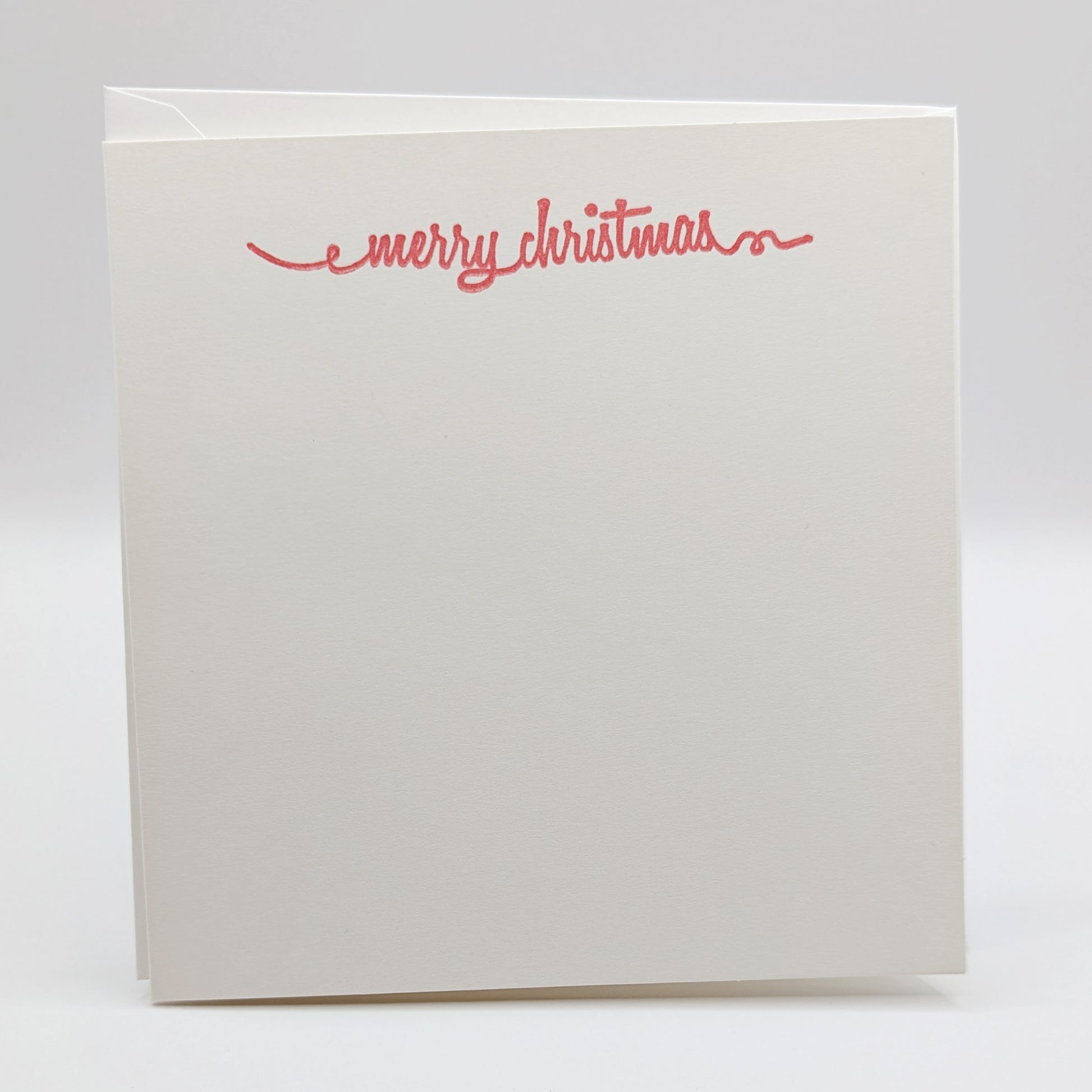 merry Christmas in a script font, stamped in red ink onto a white card comes with matching envelope